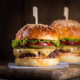 Dwa burgery w bułkach z sezamem, z wołowiną, serem i warzywami — propozycja podania zestawu